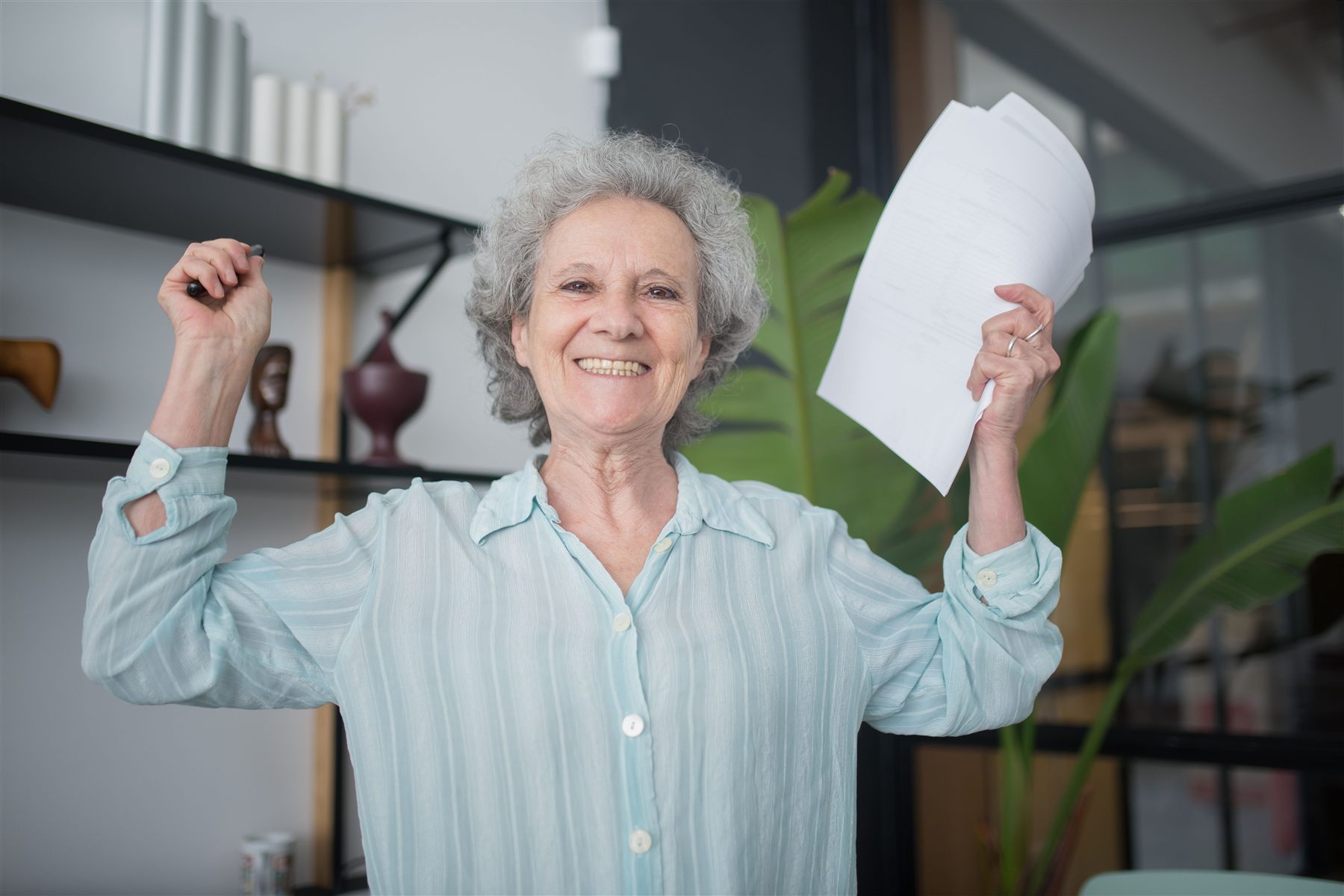 Mulher idosa celebrando uma conquista após organizar seus documentos